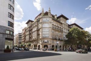 un gran edificio de piedra en una calle de la ciudad con coches en Apartamento en Gran Vía, en Bilbao