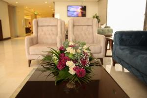 sala de estar con mesa y ramo de flores en Gloria Hotel, en Amán