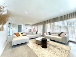 una sala de estar con muebles blancos y ventanas grandes. en Luxe Terrigal beach Ocean View with Infinity pool en Wamberal