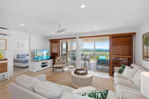 a living room with white furniture and a view of the ocean at Crest Premium View Apartment 32 in Noosa Heads