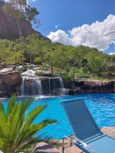 a pool with a waterfall and a chair in front at Pousada Jipe Canastra in Capitólio