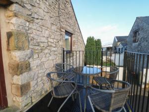 a balcony with chairs and a table and a stone wall at The Loft in Buxton