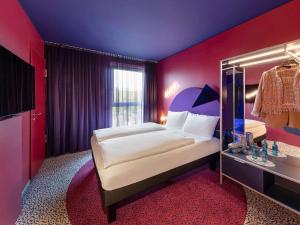 ibis Styles Muenchen Perlach في ميونخ: غرفة نوم مع سرير مزدوج كبير ومرآة