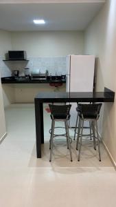 una cucina con tavolo nero e 2 sedie di Encanto da Vila a Morro de São Paulo