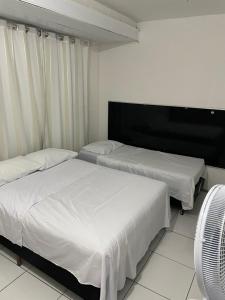 a bedroom with two beds and a fan at Suite Proximo a Praia in Arraial do Cabo