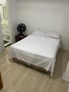 a bedroom with a bed with white sheets and a wooden floor at Suite Proximo a Praia in Arraial do Cabo +2 photos