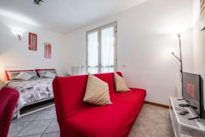 Sofá rojo en una habitación con cama en Delizioso flat in centro storico - Free WiFi & Netflix, en Massa Lombarda