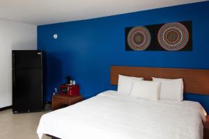 a bedroom with a blue wall and a bed at American Inn in Baton Rouge