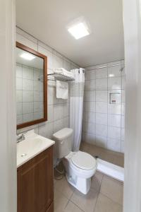 a bathroom with a toilet and a sink and a mirror at American Inn in Baton Rouge