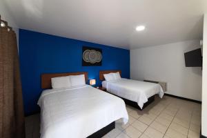 a bedroom with two beds and a blue wall at American Inn in Baton Rouge +8 photos