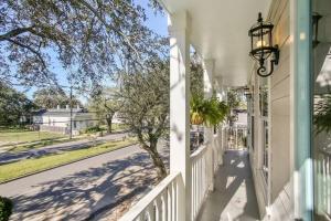 a porch of a white house with a tree and a street at La Belle Cottage II 2queenbeds 10min to French Qtr in New Orleans