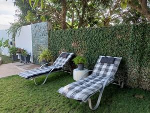 zwei Stühle auf dem Rasen neben einem Zaun in der Unterkunft VickyBella's FUNadise Private Resort in Cauayan