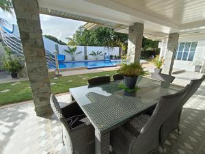 eine Terrasse mit einem Tisch, Stühlen und einem Pool in der Unterkunft VickyBella's FUNadise Private Resort in Cauayan