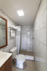 a bathroom with a toilet and a shower and a sink at American Inn in Baton Rouge