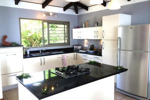 eine Küche mit weißen Schränken und einem Kühlschrank aus Edelstahl in der Unterkunft TAHITI - La Villa Vahineria Dream 5 pax in Punaauia