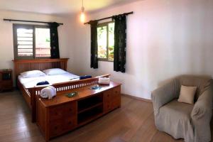 a bedroom with a bed and a couch and a chair at TAHITI - La Villa Vahineria Dream 5 pax in Punaauia