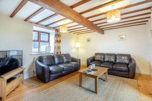 a living room with two leather couches and a table at Bwythyn-y-Wennol in Abersoch