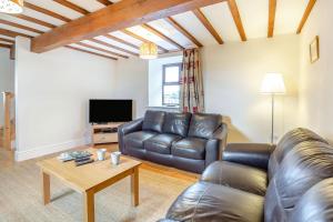 a living room with a leather couch and a table at Bwythyn-y-Wennol in Abersoch