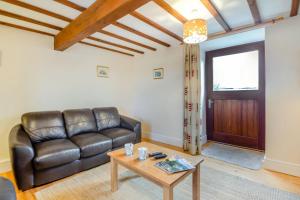 a living room with a leather couch and a table at Bwythyn-y-Wennol in Abersoch