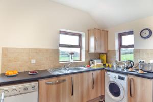a kitchen with a sink and a washing machine at Bwythyn-y-Wennol in Abersoch