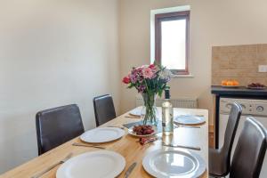 a dining room table with plates and a vase of flowers at Bwythyn-y-Wennol in Abersoch