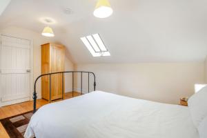 a bedroom with a bed with white sheets and a skylight at Bwythyn-y-Wennol in Abersoch
