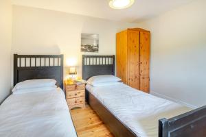 two twin beds in a bedroom with a wooden cabinet at Bwythyn-y-Wennol in Abersoch
