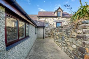 a stone wall next to a stone house at Bwythyn-y-Wennol in Abersoch