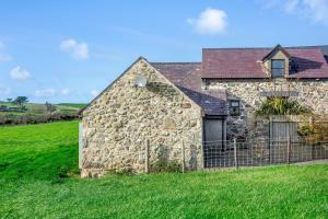 an old stone building in a green field at Bwythyn-y-Wennol in Abersoch