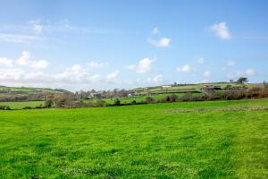 a green field with a blue sky and green grass at Bwythyn-y-Wennol in Abersoch