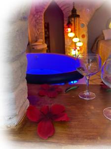 een badkamer met een blauw bad en 2 glazen en bloemen bij Casas cueva El Castaño in Pampaneira