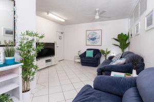 a living room with blue couches and a flat screen tv at Carinya Gardens 15 in Forster