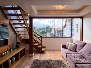 un soggiorno con un divano e una grande finestra di Apartamentos Dioserra CENTRO by Achei Gramado a Gramado