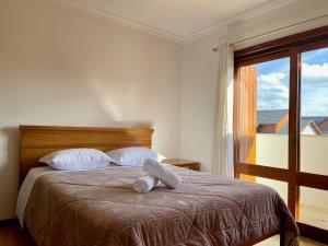 una camera da letto con un letto con una grande finestra di Apartamentos Dioserra CENTRO by Achei Gramado a Gramado
