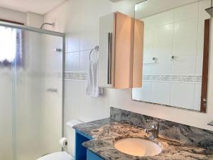 un bagno con lavandino, WC e specchio di Apartamentos Dioserra CENTRO by Achei Gramado a Gramado Altre 53 foto