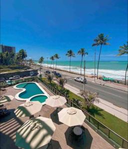 een uitzicht op het strand vanaf een resort met parasols bij Flat Suites Super Luxo in Maceió