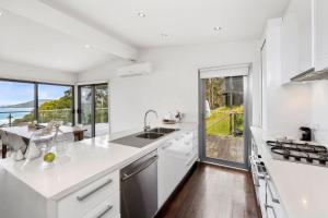 a white kitchen with a view of the ocean at Summerhills House - BYO Linen in Lorne