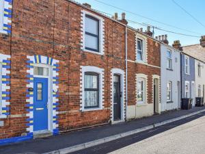 een bakstenen gebouw met een blauwe deur op een straat bij Gwens House in Melcombe Regis