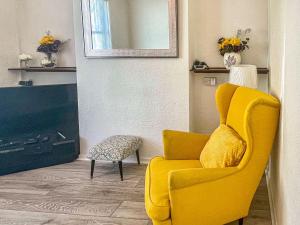 een gele stoel in een woonkamer met een spiegel bij Gwens House in Melcombe Regis