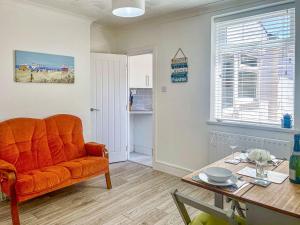 een woonkamer met een oranje bank en een tafel bij Gwens House in Melcombe Regis