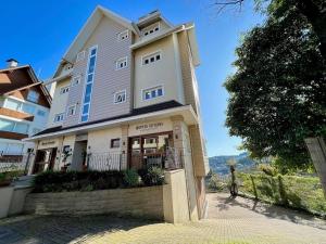 un gran edificio blanco con una valla delante en Apartamentos Villa Di Favero CENTRO by Achei Gramado, en Gramado