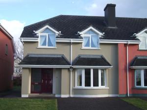 ein Haus mit schwarzem Dach und weißen Fenstern in der Unterkunft 29 Waterville Links Holiday Home in Waterville