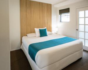 a bedroom with a large white bed with a blue blanket at Tasman Holiday Parks - North Star in Hastings Point