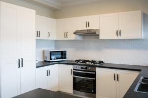 a kitchen with white cabinets and a stove and a microwave at Tasman Holiday Parks - North Star in Hastings Point