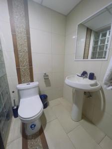 a white bathroom with a toilet and a sink at Hotel Boutique The Royalty in Guayaquil