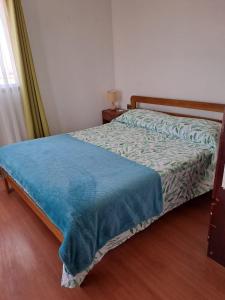 een slaapkamer met een bed met een blauwe deken erop bij Depto. equipado para 6 personas a 7 min. Bahía Inglesa in Caldera