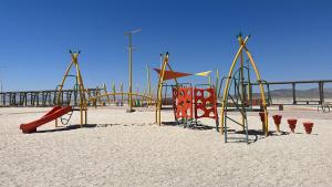 um parque infantil numa praia de areia com uma estrutura de brincar em Depto. equipado para 6 personas a 7 min. Bahía Inglesa em Caldera