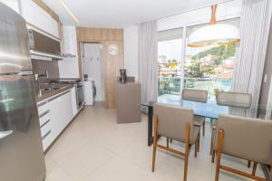 cocina con mesa con sillas y comedor en Boulevard 221D - Excelente apartamento em condomínio de luxo no centro de Bombinhas - Piscina - Jacuzzi - Academia - Portaria 24h, en Bombinhas