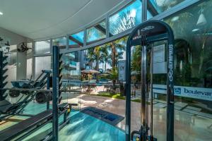 a gym in a building with a swimming pool at Boulevard 221D - Excelente apartamento em condomínio de luxo no centro de Bombinhas - Piscina - Jacuzzi - Academia - Portaria 24h - (Consultar serviços de roupa de cama e banho) in Bombinhas