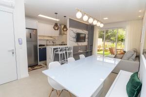 cocina y sala de estar con mesa blanca y sillas en Caraíbas 01 - Excelente apartamento garden 2 suítes - À poucos metros da praia, en Bombinhas